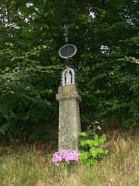litinový křížek s kamenným podstavcem v Jindřichovicích u silnice při výjezdu na Kolinec
