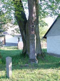 litinový křížek s kamenným podstavcem pod lipami ve Smrčí